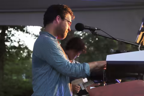 Alexander Ferguson is playing keyboard at an outdoor event.